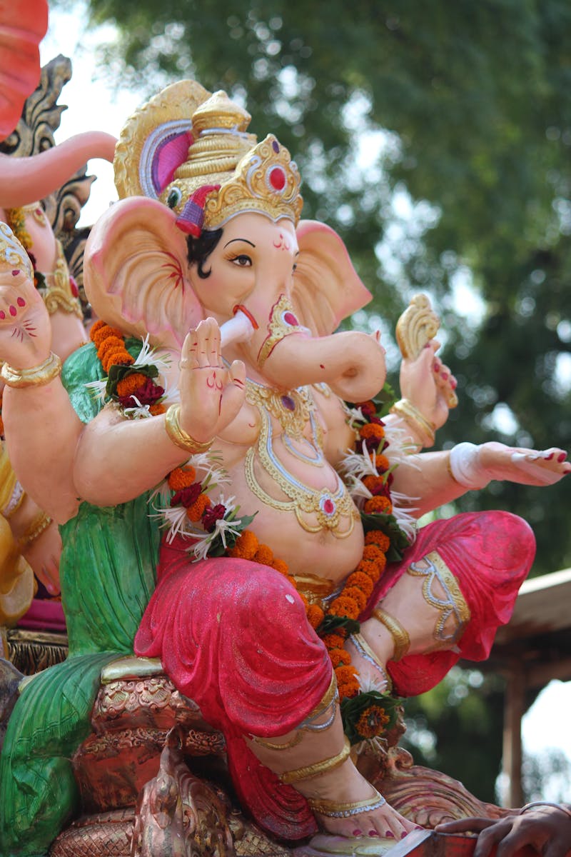 Vibrant and intricately designed Ganesh statue in outdoor festival setting.