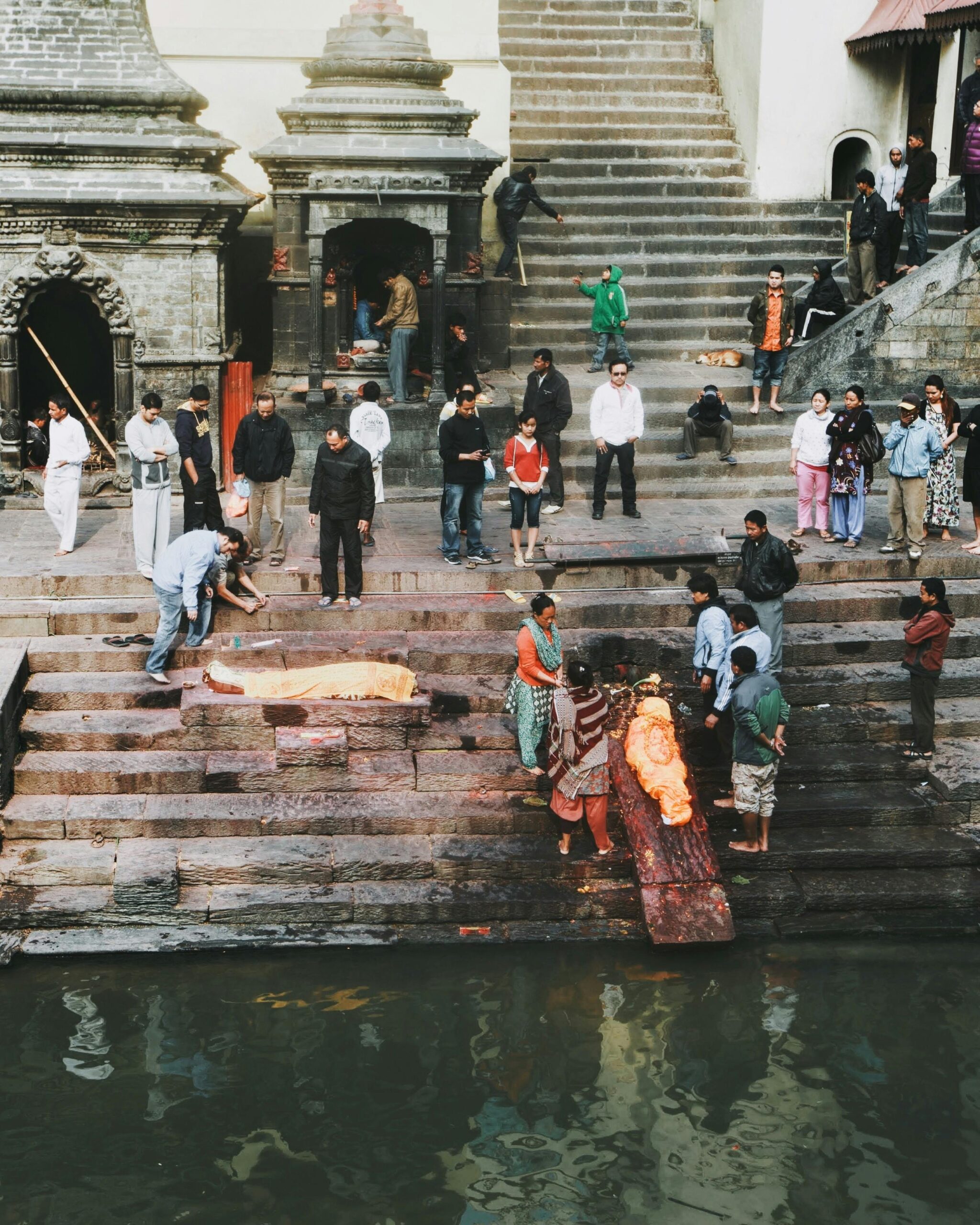 A group gathers for a traditional ceremony on the steps near a sacred river at Pashupatinath Temple in Kathmandu, Nepal.