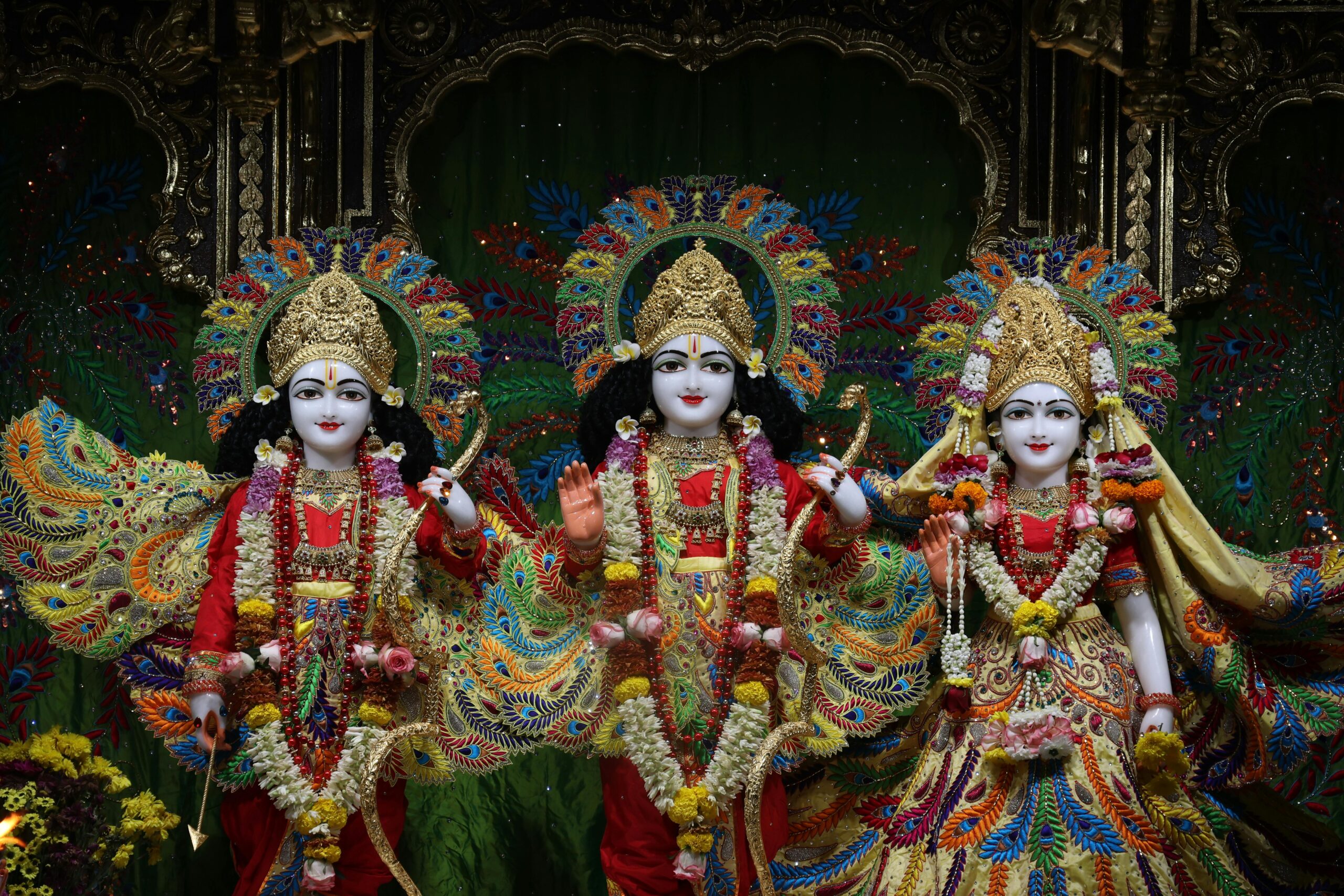 Colorful statues of Hindu deities adorned with intricate garlands in a richly decorated temple.