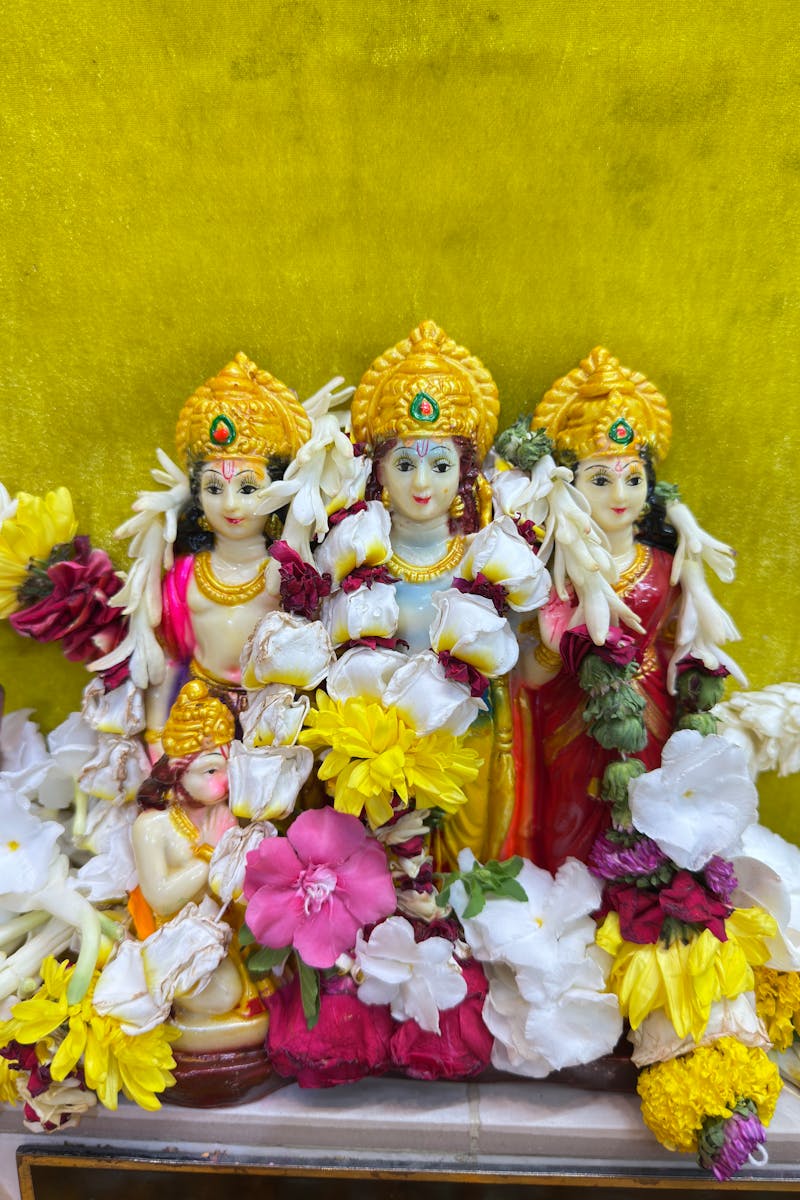 Decorative Hindu deities adorned with vibrant flowers on a colorful backdrop.