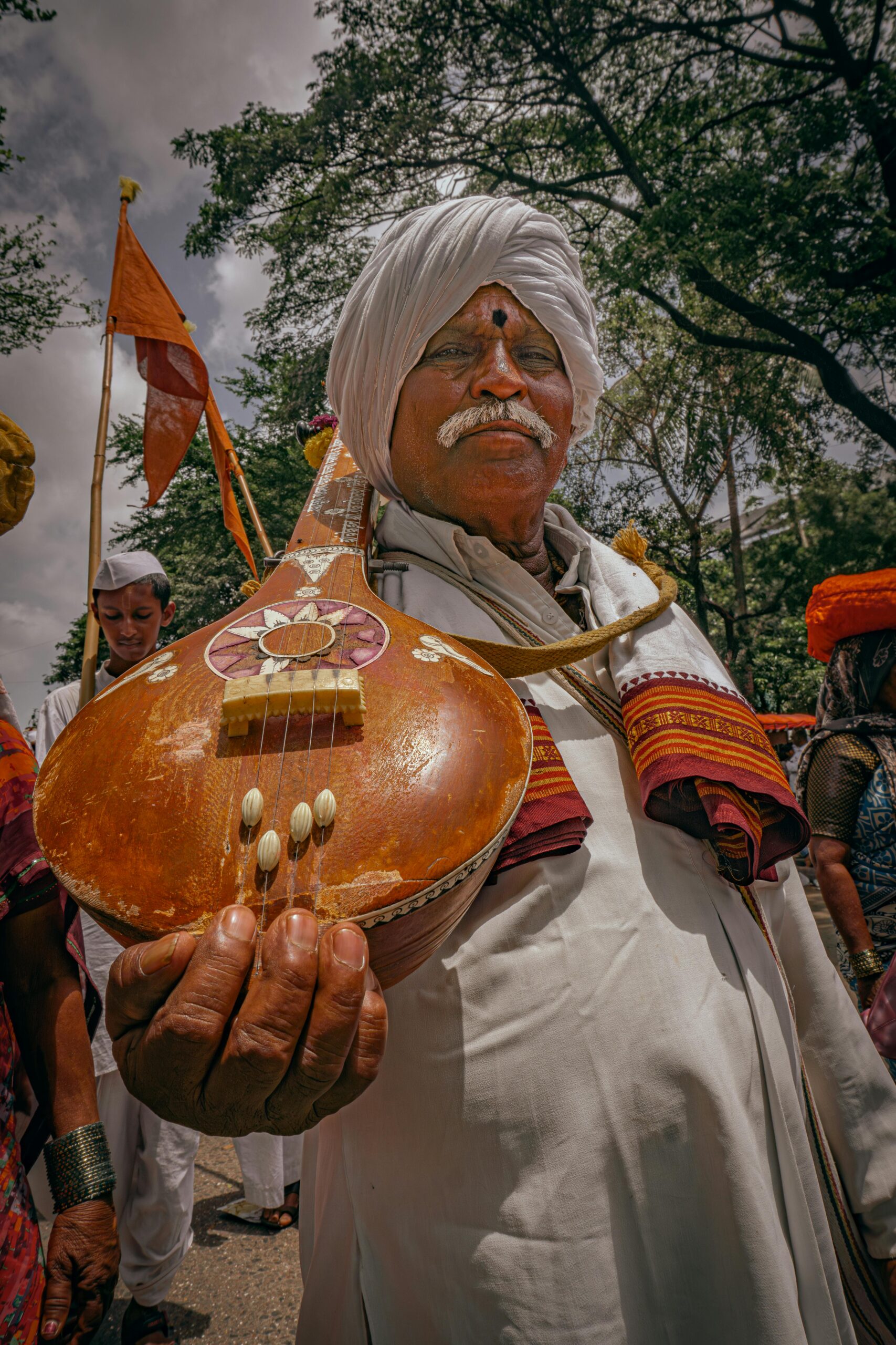 A musician holding an ektara during a cultural procession in Pune, India.