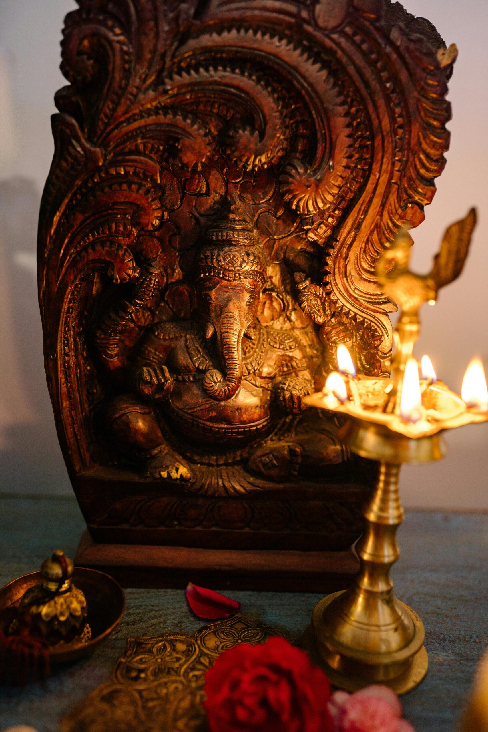 A beautifully carved Ganesha statue illuminated by traditional oil lamps, symbolizing spirituality.
