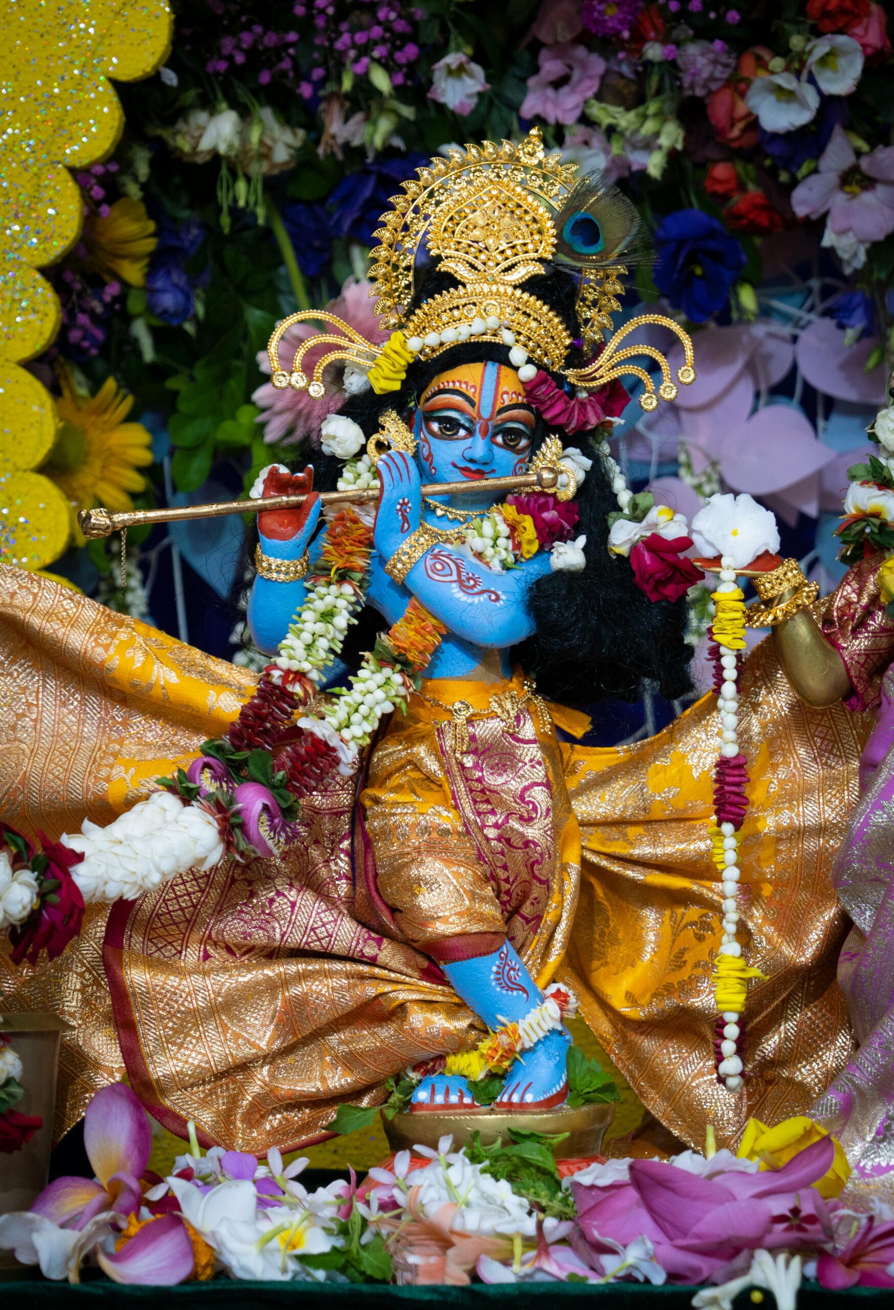 A colorful Hindu deity figurine adorned with flowers and vibrant attire, symbolizing Indian cultural heritage.