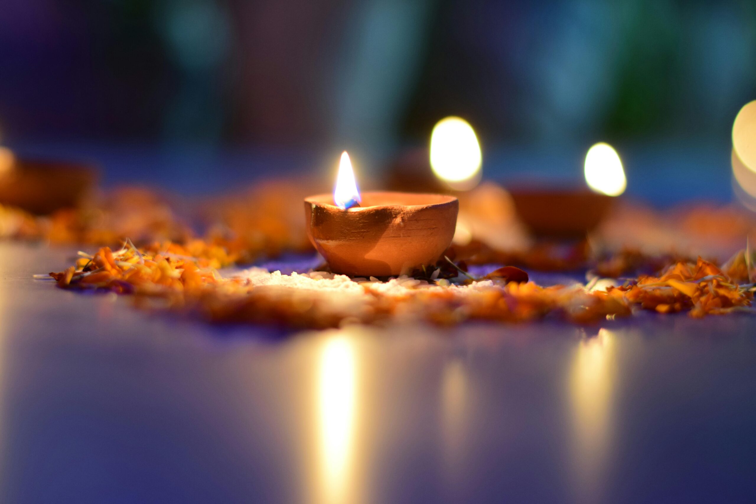 A warm and atmospheric close-up of a lit clay diya surrounded by flower petals, perfect for festive themes.