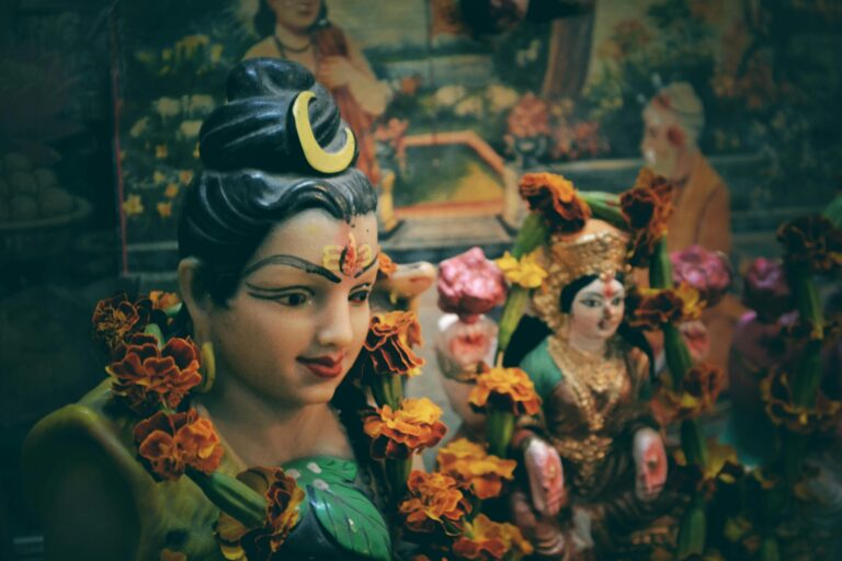 Close-up of Hindu deity statues adorned with marigold flowers in a vibrant cultural setting.